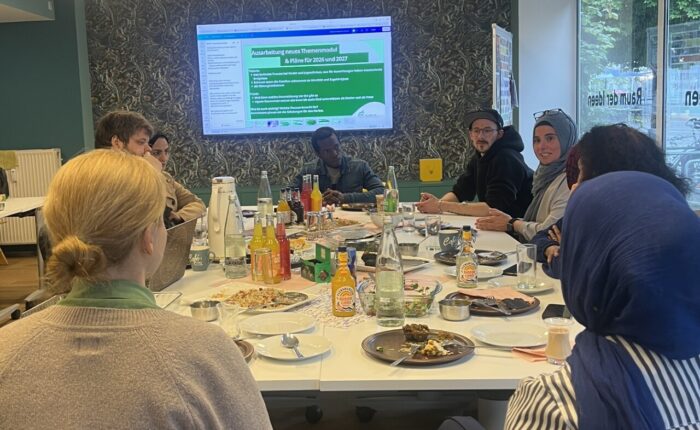 Mitarbeiter des Projekts Empower Migrants sitzen an einem großen Tisch und planen ein neues Themenmodul.