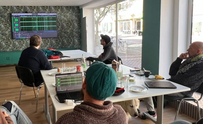 Mitarbeiter des Projekts TeilhabeDigital sehen sich Audiodateien auf einem Smartscreen an.
